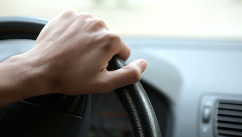 Close-up of a male hand on steering wheel in a modern car in the UK (steering wheel on the right)